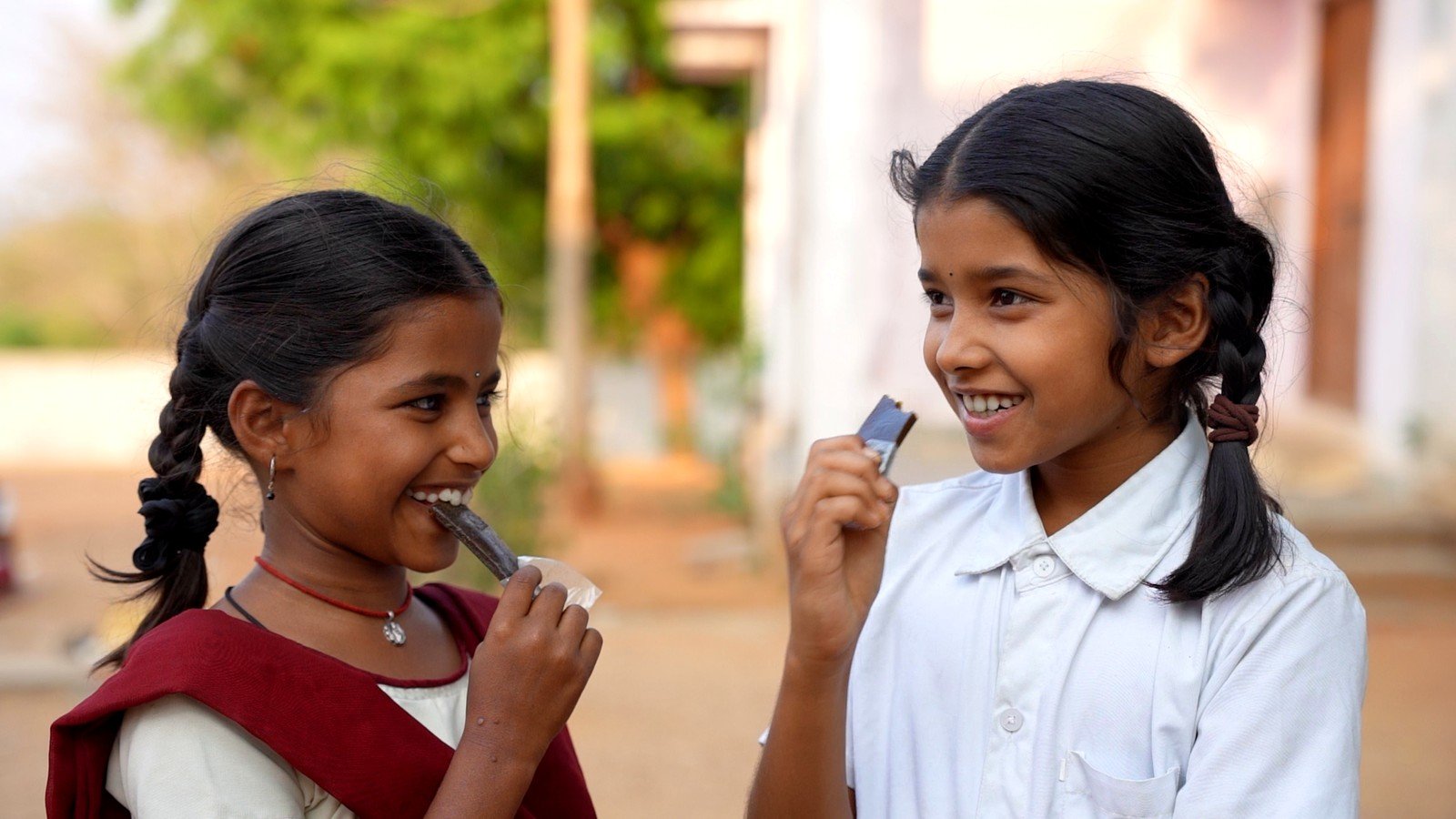 Two schoolgirls sharing a laugh while eating Mosachi's Iron Fruit Bar